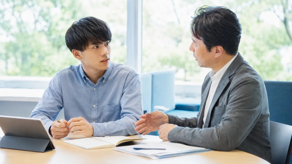 明るい相談スペースで資格選びについて話す学生とアドバイザー